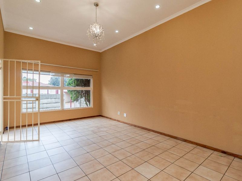 Spacious and bright living area featuring neutral tiled flooring, recessed downlighting, and a secure entrance gate, offering a blank canvas for personalization.