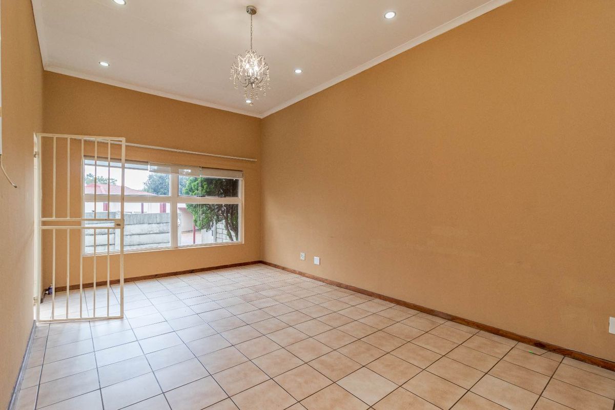 Spacious and bright living area featuring neutral tiled flooring, recessed downlighting, and a secure entrance gate, offering a blank canvas for personalization.