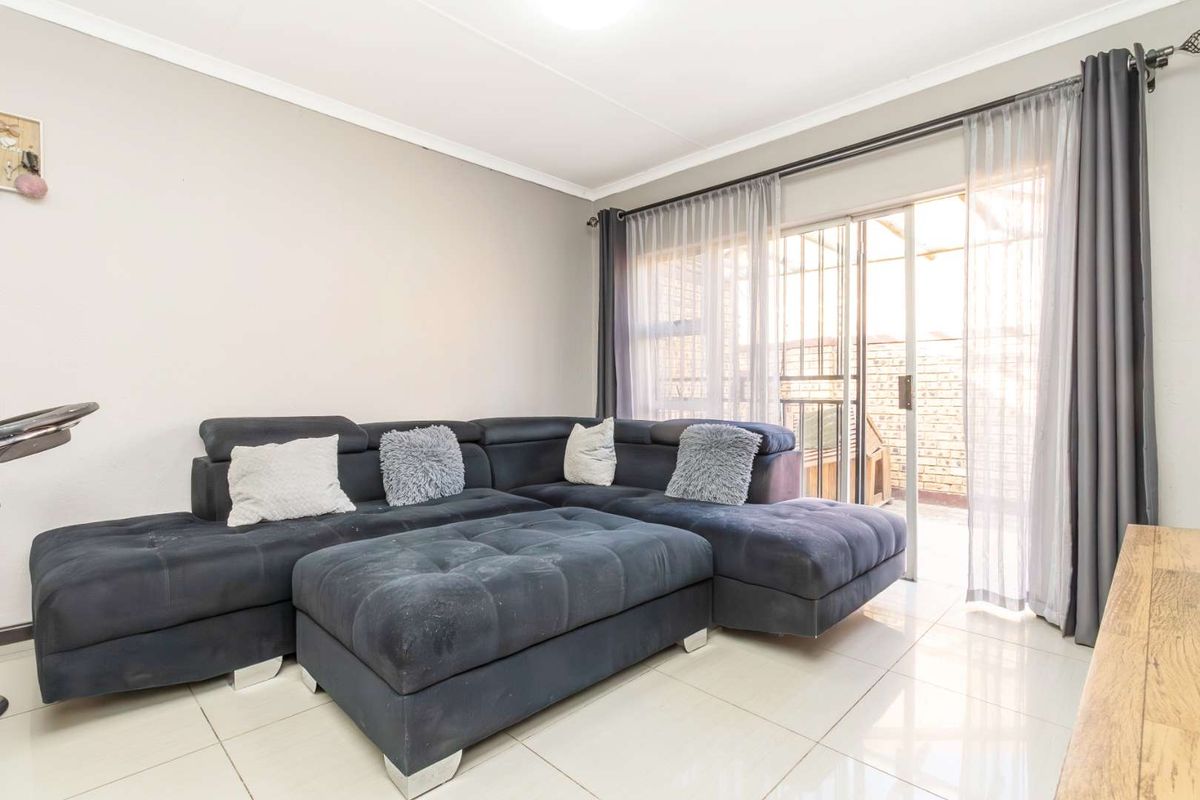 A bright living room featuring large format floor tiles and sliding glass doors providing direct access to an outdoor patio area.