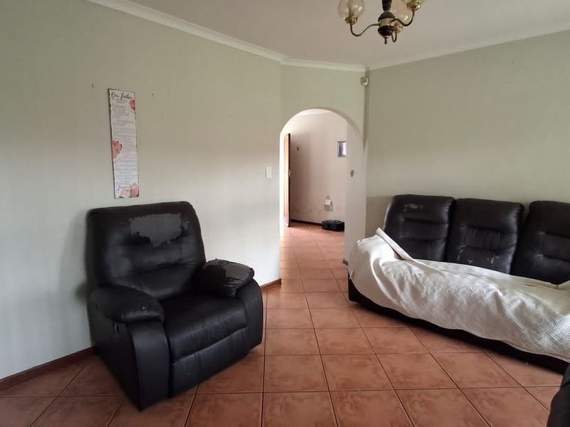 A living room featuring tiled flooring and an arched entryway, providing a neutral base for potential interior updates and modernization.