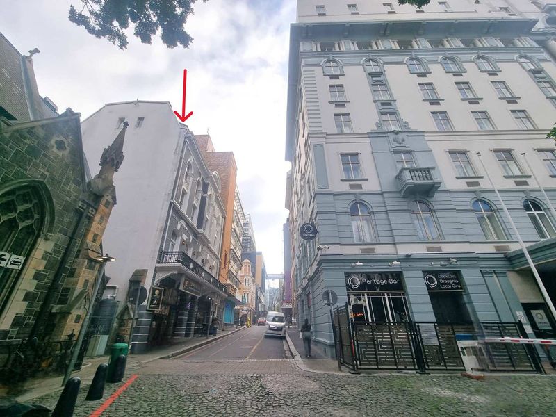 A street-level view of an urban apartment location featuring historic architecture, cobblestone paving, and surrounding commercial buildings.