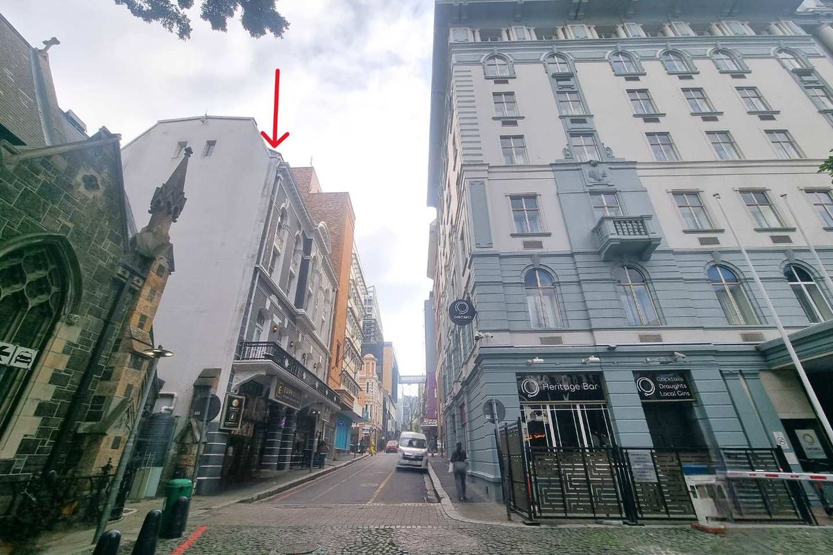 A street-level view of an urban apartment location featuring historic architecture, cobblestone paving, and surrounding commercial buildings.
