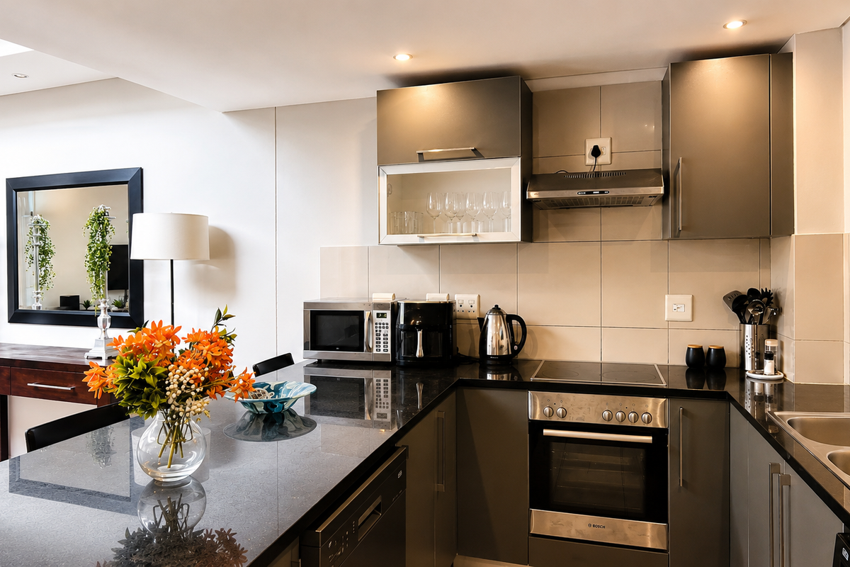 Modern kitchen featuring sleek grey cabinetry, granite countertops, integrated stainless steel appliances, and a tiled backsplash, offering a functional and contemporary cooking space.