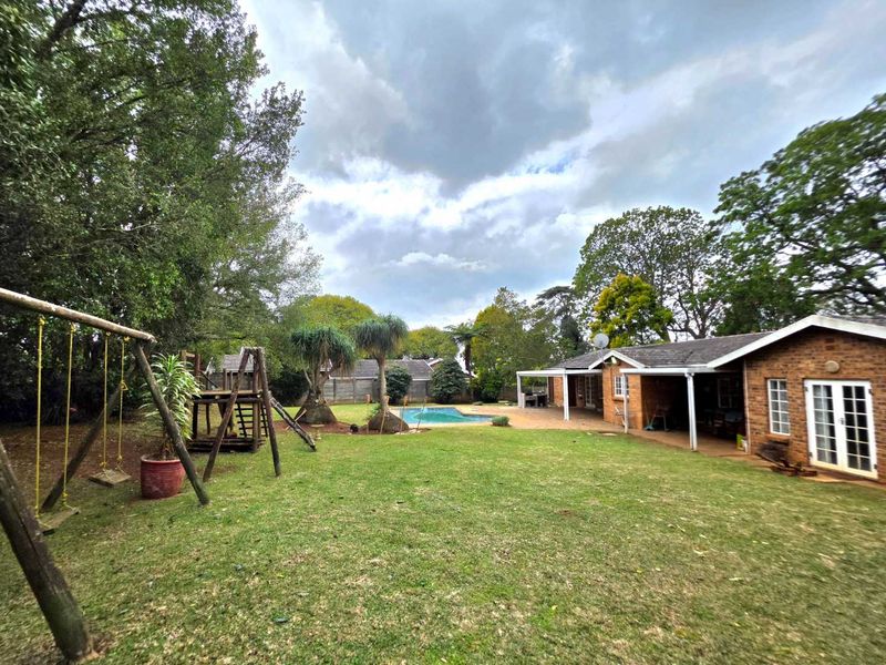 Spacious rear garden featuring a swimming pool, covered patio area, and established lawn, providing an ideal space for outdoor family recreation.