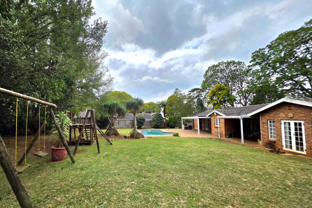 Spacious rear garden featuring a swimming pool, covered patio area, and established lawn, providing an ideal space for outdoor family recreation.