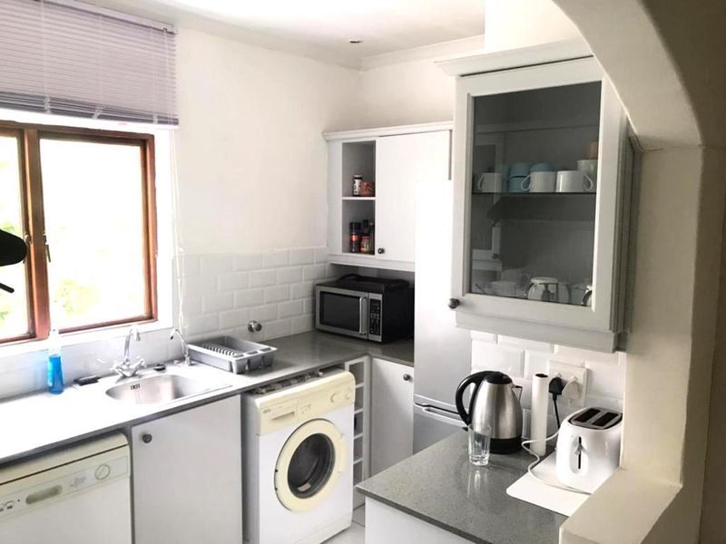 A functional kitchen featuring white cabinetry, subway tile backsplash, stone-look countertops, and dedicated space for laundry and kitchen appliances.