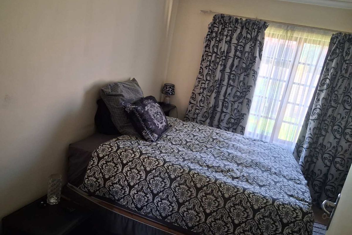 A bedroom featuring a large window with curtain tracks and natural light, providing a functional space for rest.