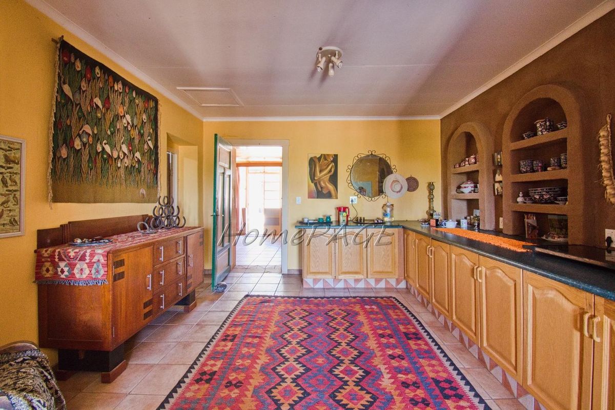 A spacious kitchen area featuring built-in wooden cabinetry, tiled flooring, and integrated arched shelving niches, providing a rustic and functional farmhouse aesthetic.
