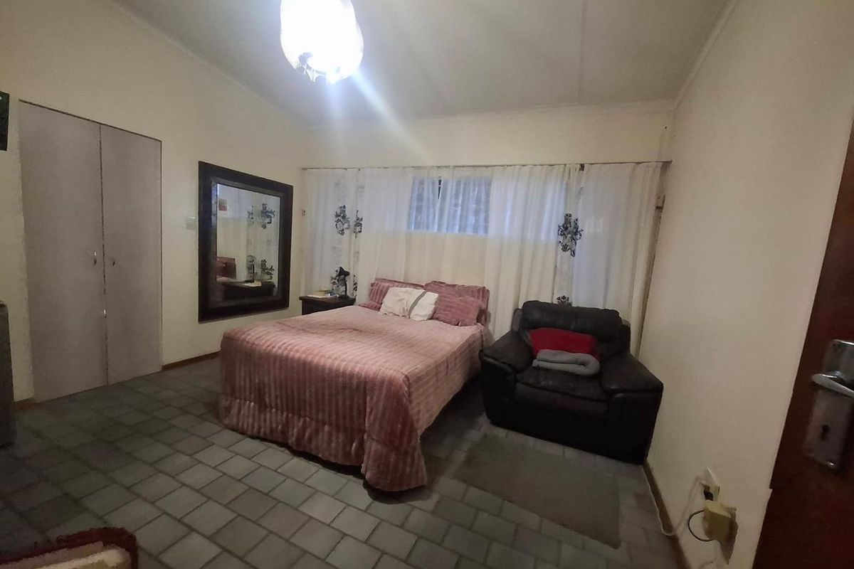 A bedroom featuring built-in cabinetry, tiled flooring, and a large wall-mounted mirror.