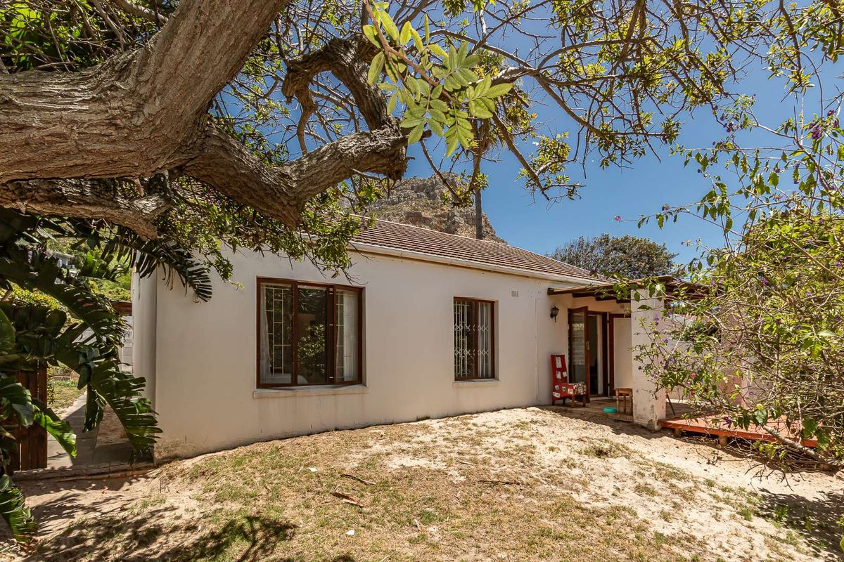 Rear view of the property featuring a simple facade, timber-framed windows with security bars, and a small covered patio area.