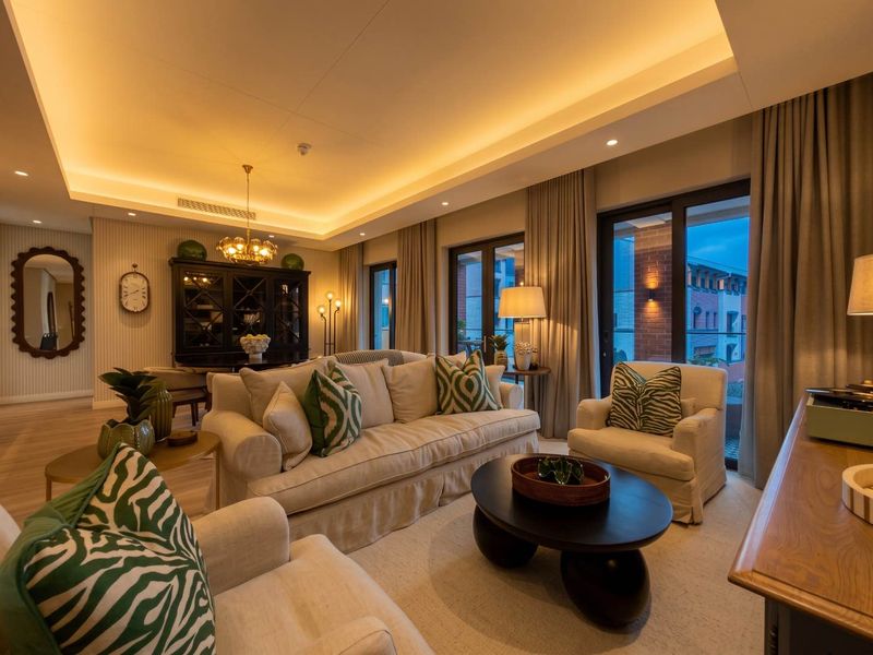 Elegant living room featuring recessed cove lighting, hardwood floors, and large sliding glass doors providing access to an outdoor balcony area.