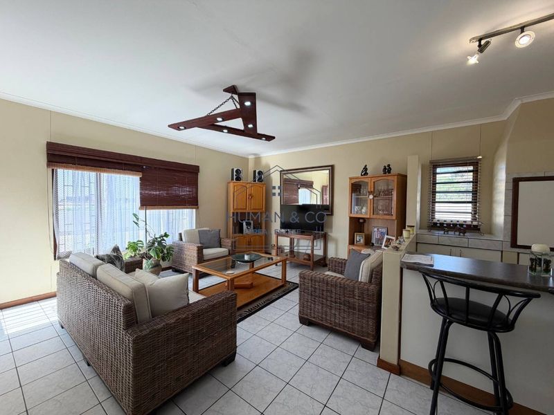 Open plan living area featuring tiled flooring, a breakfast bar, and modern track lighting, creating a functional and connected space.