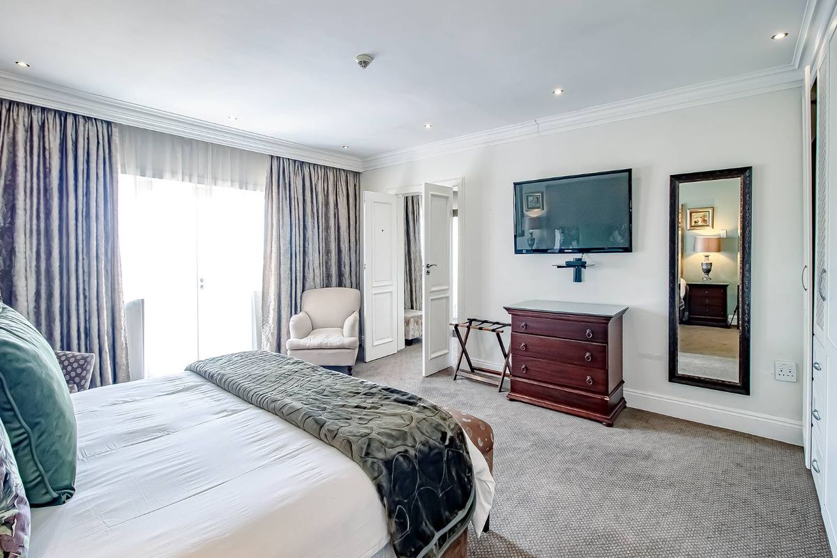 A well-maintained bedroom featuring recessed ceiling lighting, crown molding, carpeted flooring, and a glass door leading to an outdoor area.