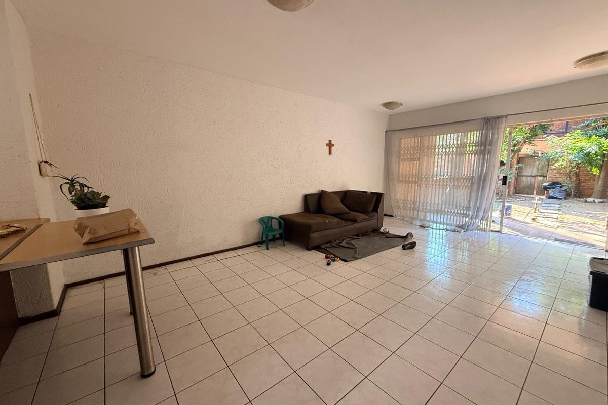 Spacious living area featuring tiled flooring and a large sliding glass door providing access to the outdoor space.