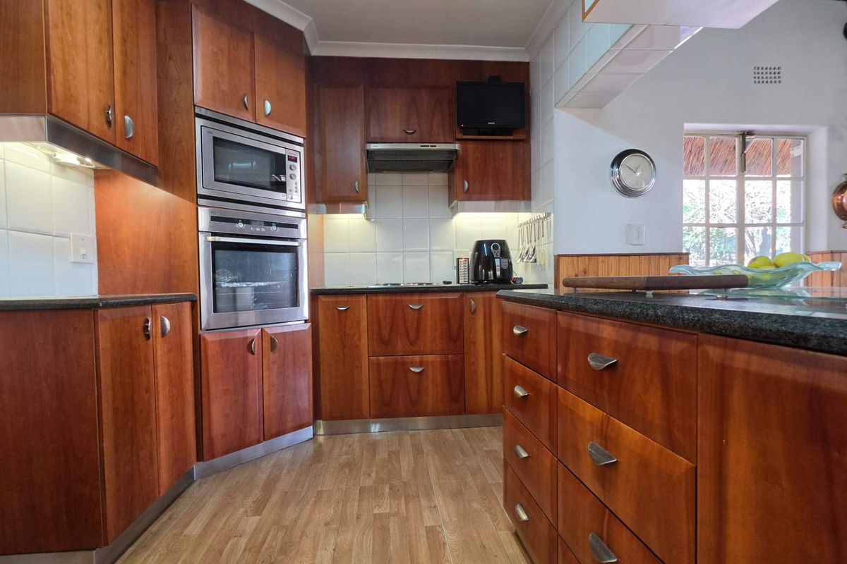 A functional kitchen featuring warm-toned wooden cabinetry, granite countertops, a built-in oven, microwave, and an integrated extractor fan.