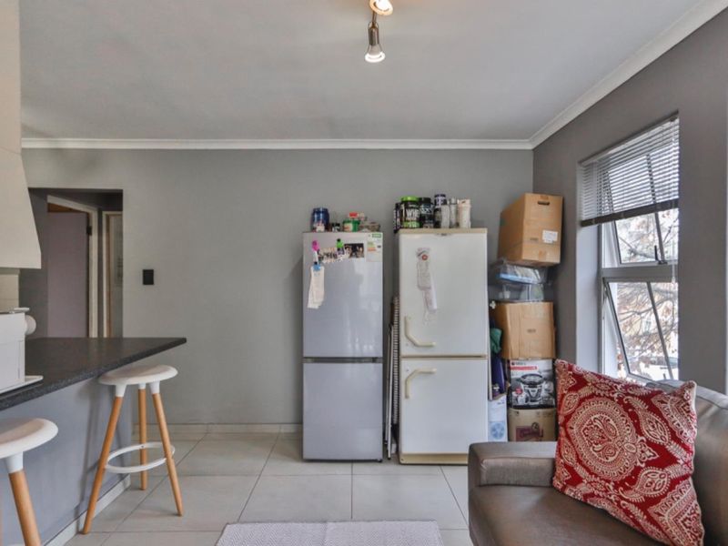 Open plan living area featuring tiled flooring, a breakfast bar, and large windows with venetian blinds, offering a functional layout for modern living.