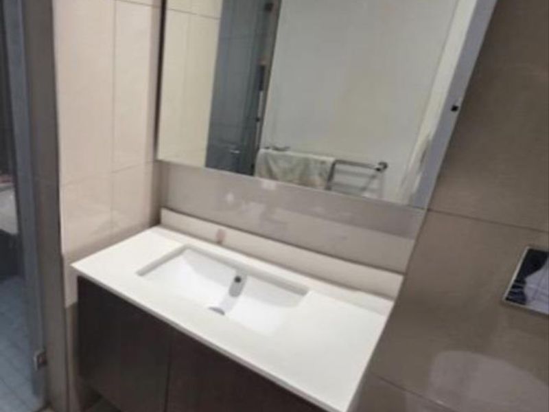 A modern bathroom featuring a wall-mounted vanity with an integrated basin, large mirror, and neutral wall and floor tiling.
