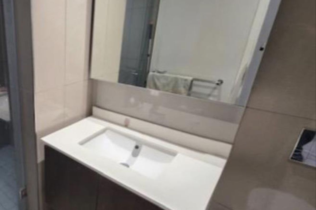 A modern bathroom featuring a wall-mounted vanity with an integrated basin, large mirror, and neutral wall and floor tiling.