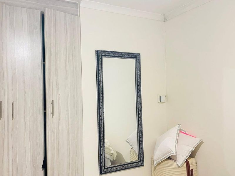 A bedroom interior featuring a modern wood-grain finish built-in wardrobe and neutral wall tones.