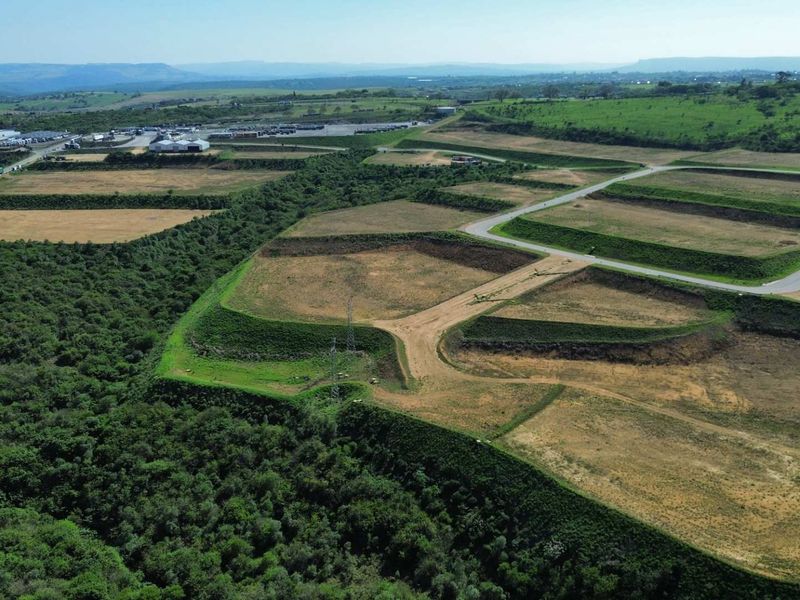 Aerial view of a large industrial development site featuring terraced land, established access roads, and surrounding natural vegetation.