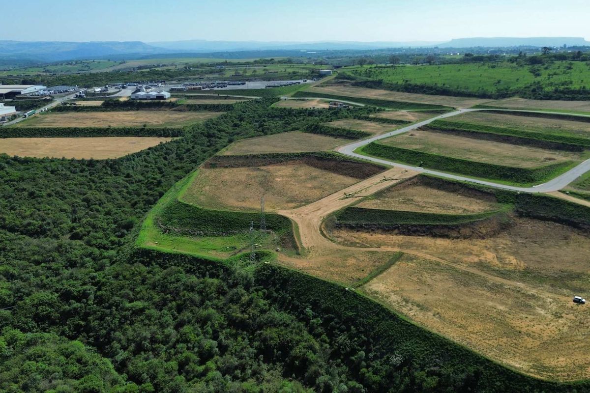 Aerial view of a large industrial development site featuring terraced land, established access roads, and surrounding natural vegetation.
