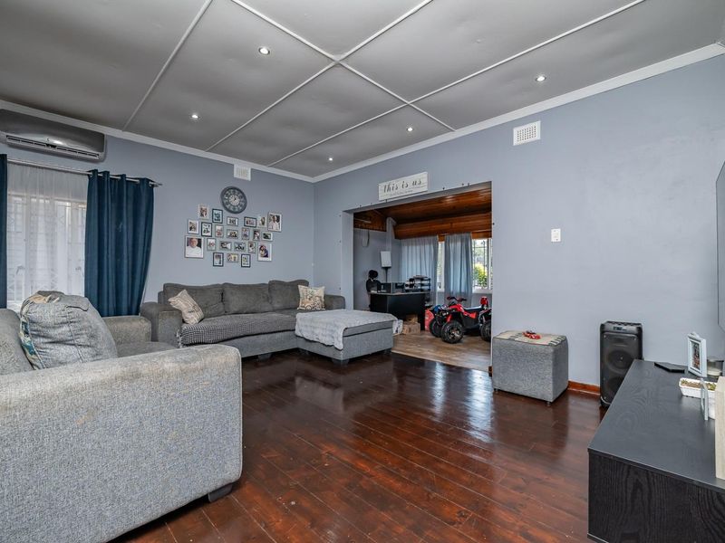Spacious living room featuring polished hardwood flooring, recessed lighting, and a wall-mounted air conditioning unit, providing a comfortable and functional living space.