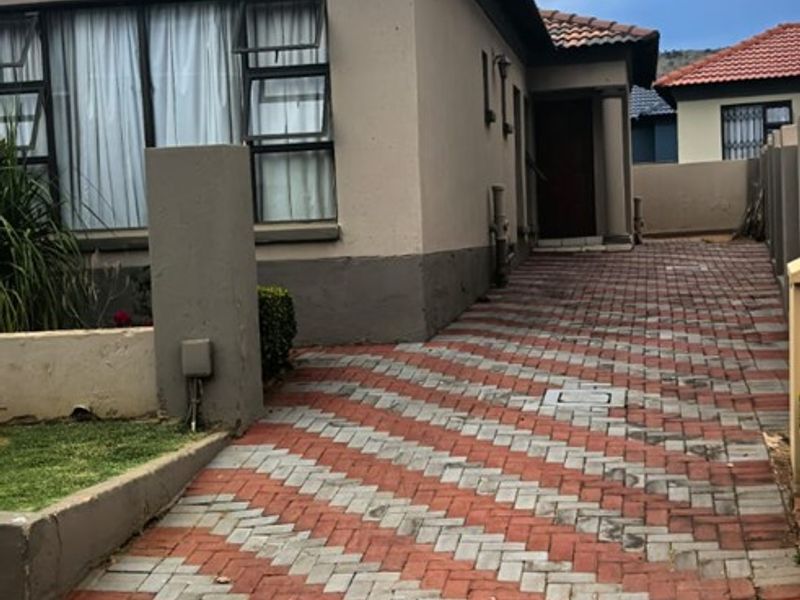 Front view of the property featuring a paved driveway, plastered exterior walls, and a tiled roof.