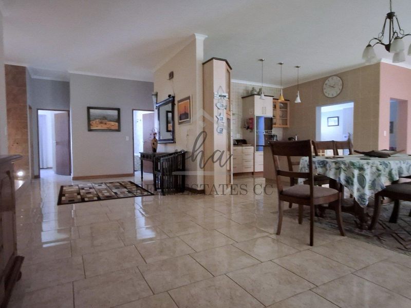 Spacious open-plan living and dining area featuring tiled flooring, neutral walls, and an integrated kitchen space with cabinetry.