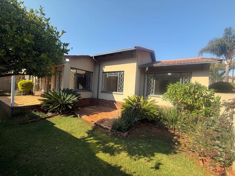 Rear view of the townhouse featuring a brick-paved patio, landscaped garden, and terracotta tiled roof with security-fitted windows.