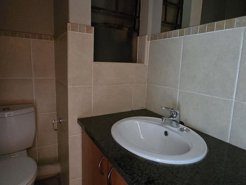 A functional bathroom featuring a vanity cabinet with a granite countertop, drop-in basin, and tiled wall finishes.