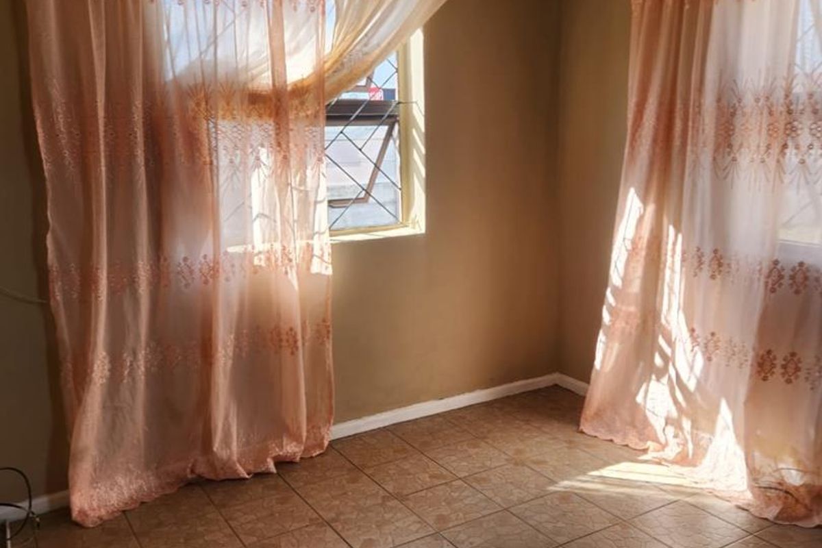 An empty bedroom featuring tiled flooring and security bars on the windows, offering a blank canvas for renovation and interior design updates.