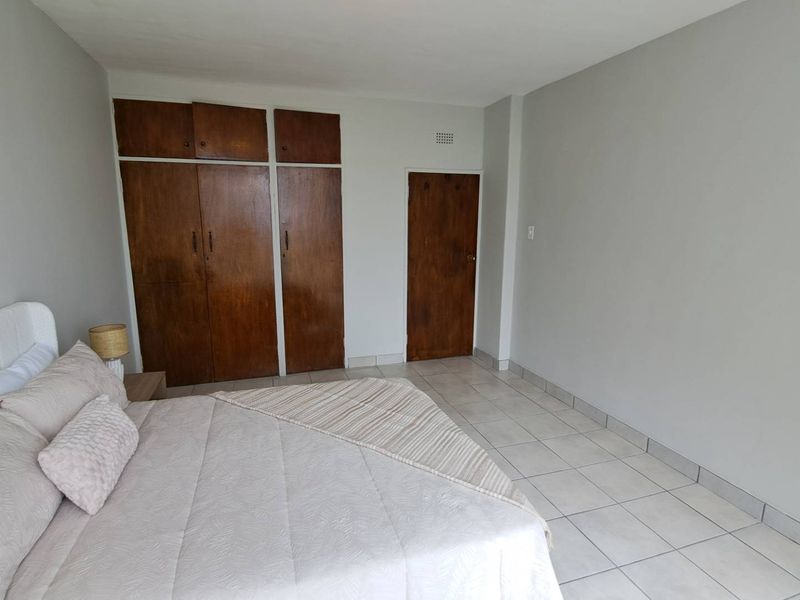 A bedroom featuring tiled flooring and built-in wooden cupboards, offering a neutral canvas for potential interior updates.
