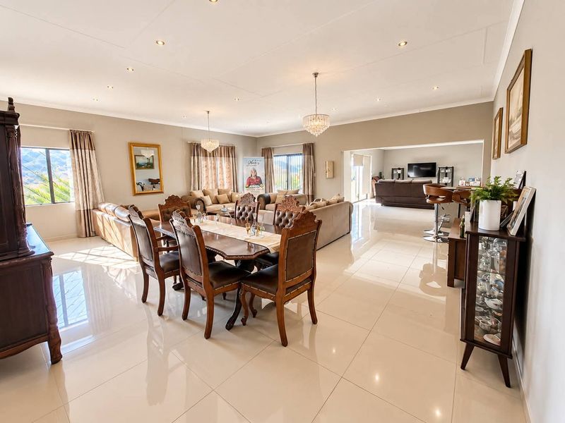 Spacious open-plan living and dining area featuring polished porcelain floor tiles, elegant crystal chandeliers, and recessed downlighting throughout the expansive interior space.