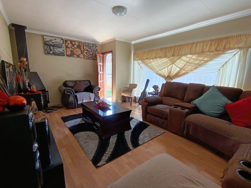 A comfortable living room featuring laminate flooring and a built-in wood-burning fireplace, offering a warm and inviting atmosphere.