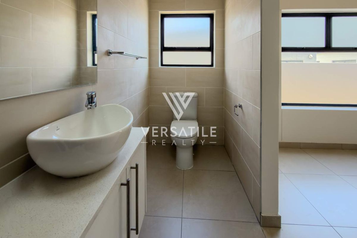 A modern bathroom featuring a vessel sink on a vanity cabinet, a toilet, and neutral wall and floor tiling.