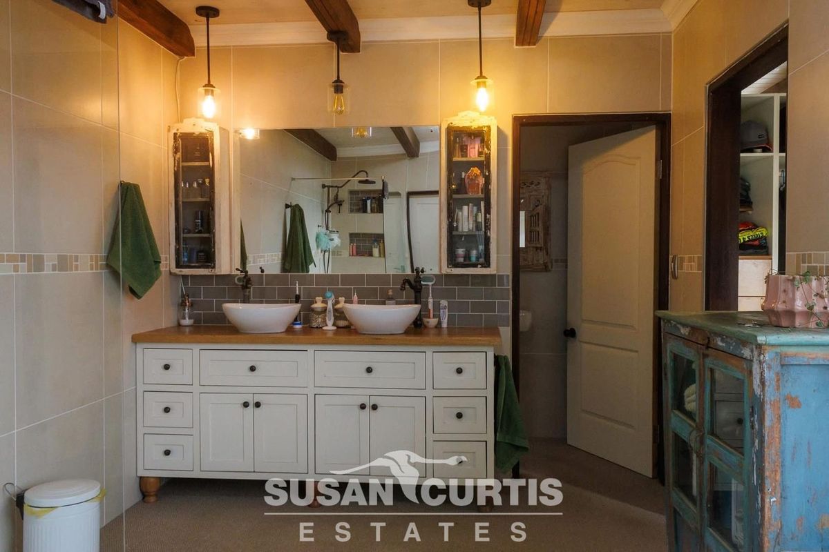 A well-appointed bathroom featuring a double vanity with vessel sinks, wooden countertop, and exposed ceiling beams.
