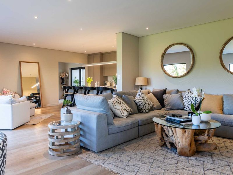 Spacious open-plan living area featuring light timber flooring, recessed lighting, and a modern kitchen with a central island and sleek cabinetry.