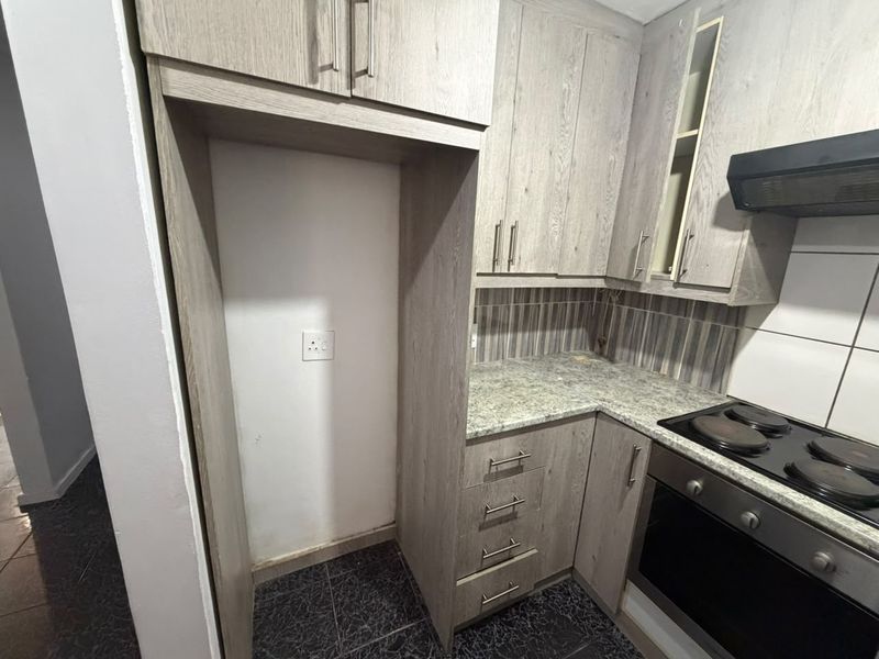 A functional kitchen featuring wood-look cabinetry, granite countertops, a built-in oven with hob, and an extractor fan, finished with a tiled backsplash.