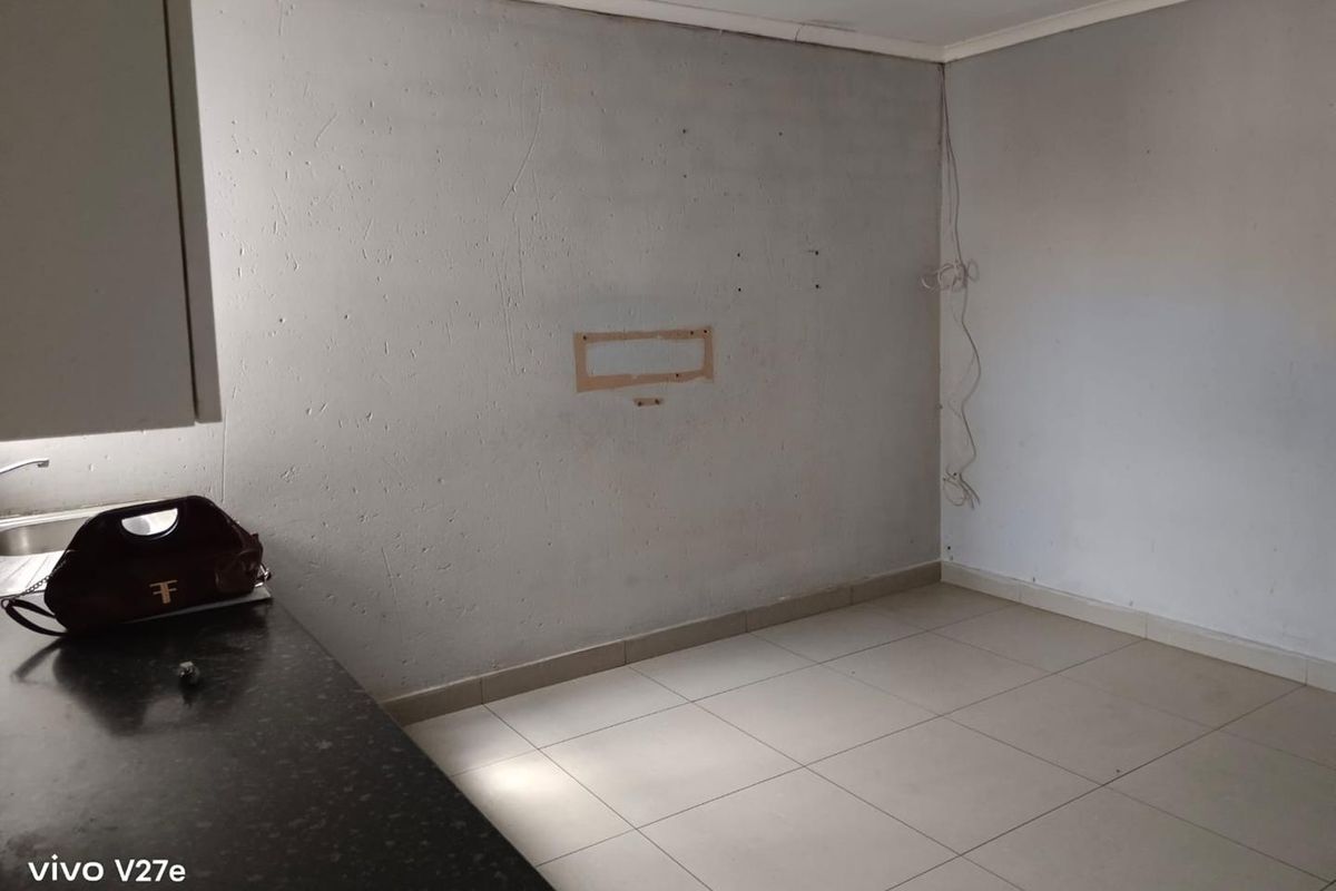 A compact kitchen area featuring tiled flooring and a granite countertop, currently requiring cosmetic updates and finishing to the wall surfaces.