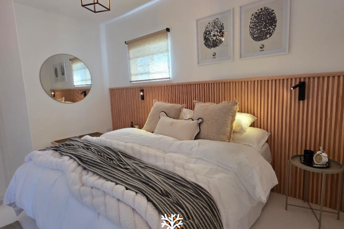 A modern bedroom featuring a stylish timber slat feature wall, integrated wall-mounted reading lights, and neutral finishes.