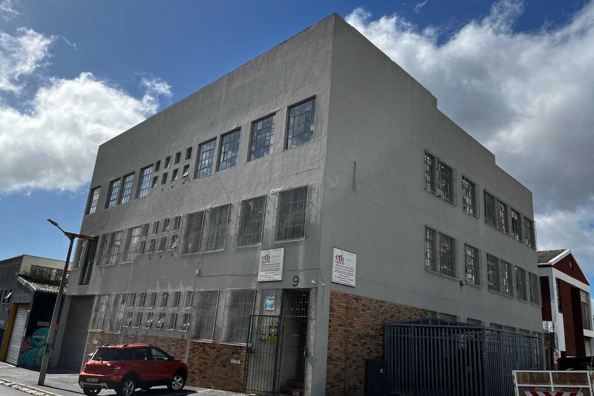 A multi-story industrial building featuring a combination of brick and rendered facade, equipped with security grilles and industrial-style windows.