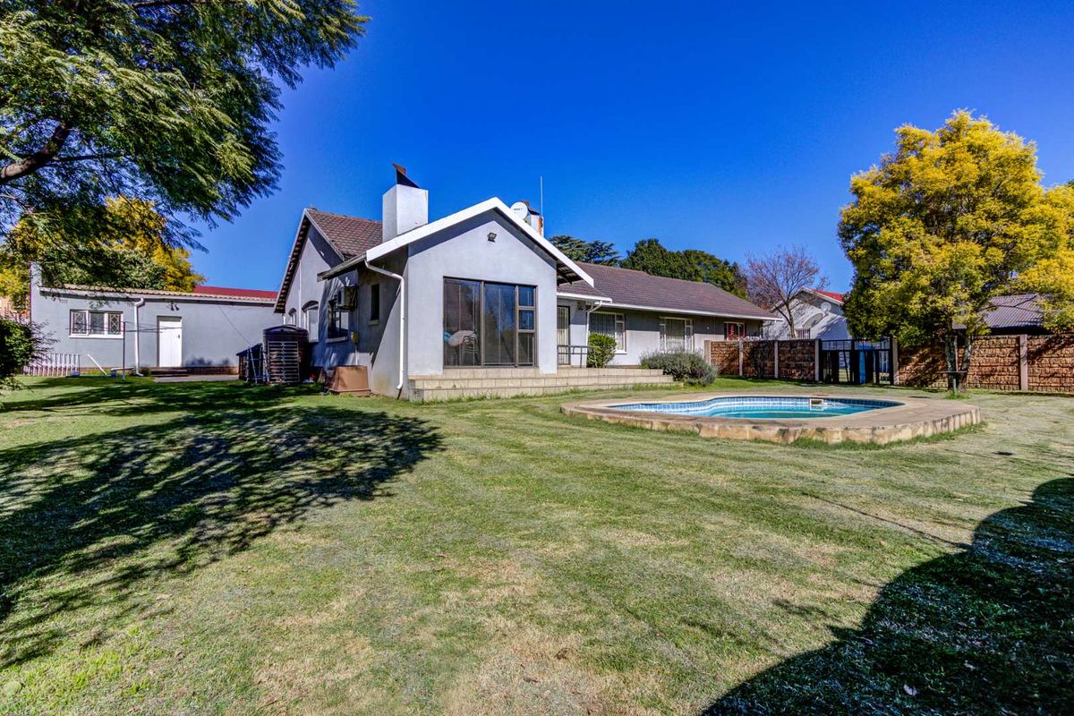 Rear view of the property featuring a spacious garden, a swimming pool, and a paved patio area attached to the main house structure.