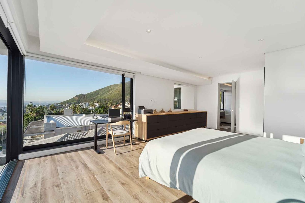 Spacious modern bedroom featuring large floor-to-ceiling windows with scenic mountain views, recessed lighting, and high-quality laminate wood flooring.