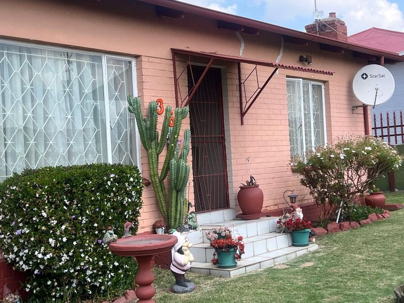 Front elevation of a single-story brick house featuring a tiled entrance, metal awning, and security gate.
