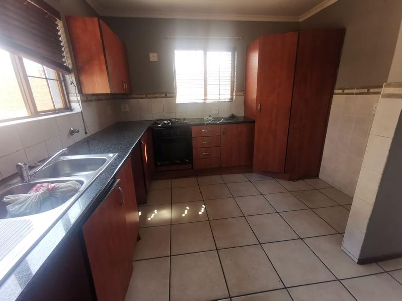 Functional kitchen featuring built-in wooden cabinetry, granite countertops, a double basin sink, and a built-in oven with gas hob.