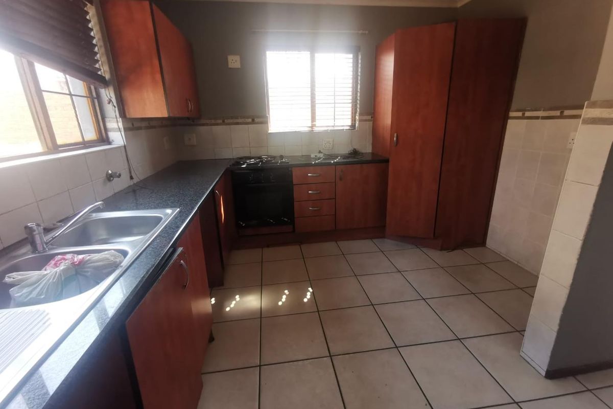 Functional kitchen featuring built-in wooden cabinetry, granite countertops, a double basin sink, and a built-in oven with gas hob.