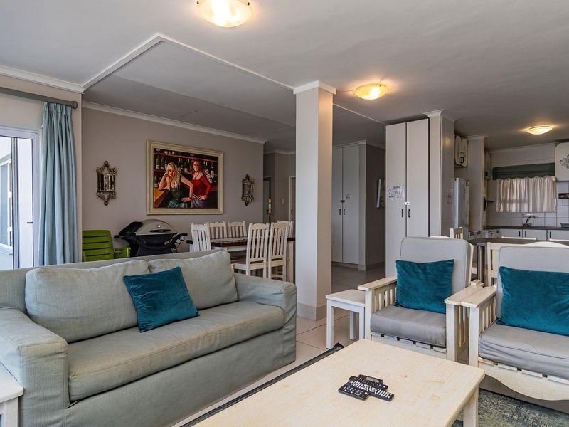 Open-plan living and kitchen area featuring tiled floors, neutral walls, and direct access to an outdoor patio through sliding glass doors.
