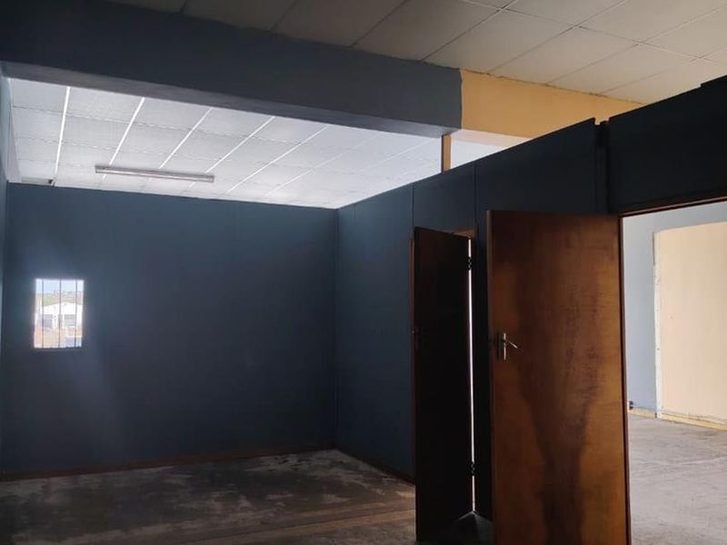 An empty office space featuring partition walls, suspended ceilings, and worn concrete flooring, suitable for renovation or commercial fit-out.