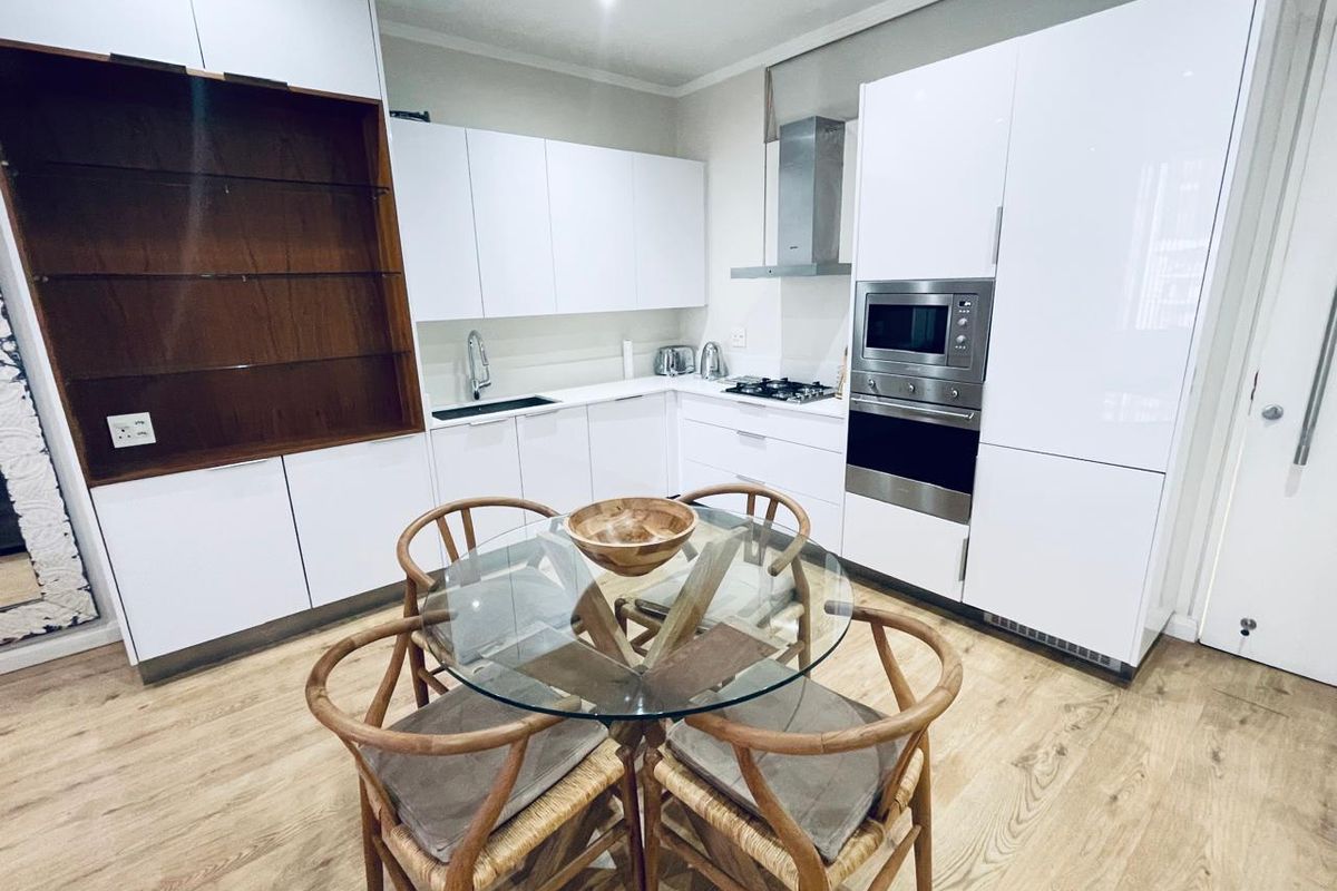 Modern kitchen featuring high-gloss white cabinetry, integrated stainless steel appliances, gas hob, and durable laminate flooring.