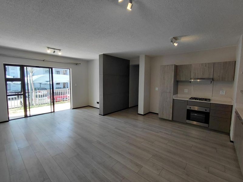 Spacious open-plan living area featuring modern kitchen cabinetry, built-in appliances, and large sliding doors leading to an outdoor space.